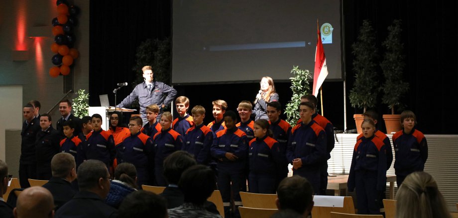 Kinder der Jugendfeuerwehr vor einer Bühne in einheitlichem Feuerwehroutfit