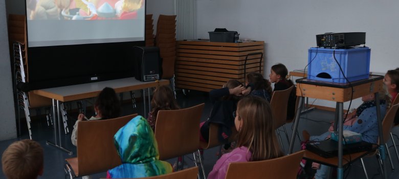 Kinder schauen einen Film auf einer Leinwand