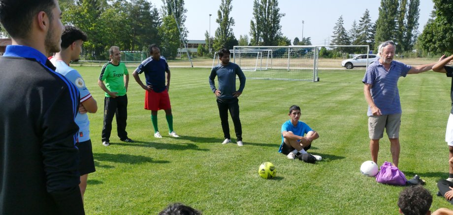 Fußballspieler sitzen und stehen im Kreis auf dem Fußballfeld