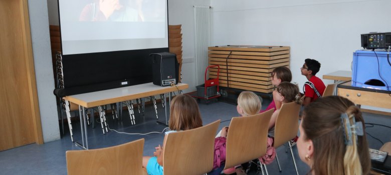 Kinder schauen einen Film, der auf einer Leinwand gezeigt wird
