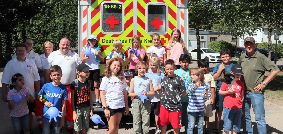 Gruppenfoto mit Kindern und DRK vor einem Rettungswagen