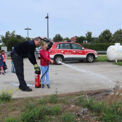 Feuerwehrmann und Kind löschen Feuer mit Feuerlöscher