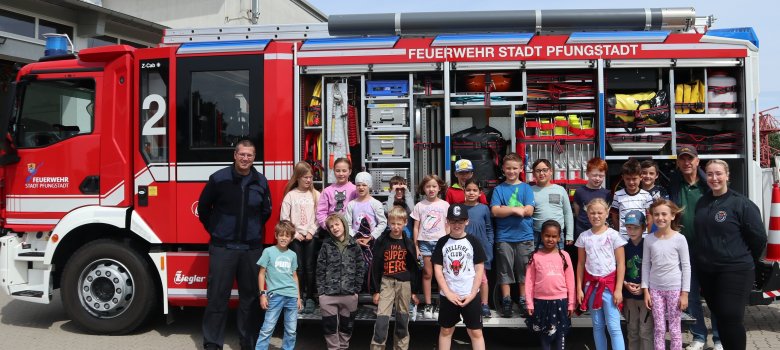 Gruppenbild mit Kindern und Feuerwehr vor einem Feuerwehrauto 